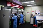 A medical worker, center, speaks with a visitor from inside the Covid-19 safety booth in the walk-thru testing center at H Plus Yangji Hospital in Seoul, South Korea, on July 24.