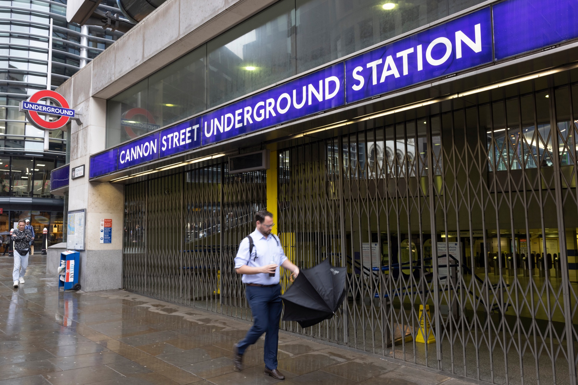 A commuter passes closed shutters at Cannon Street Station, during strikes on the underground rail service, in London.&nbsp;