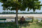 A person sits in the shade&nbsp;in front of the Po river in Calto, Italy.