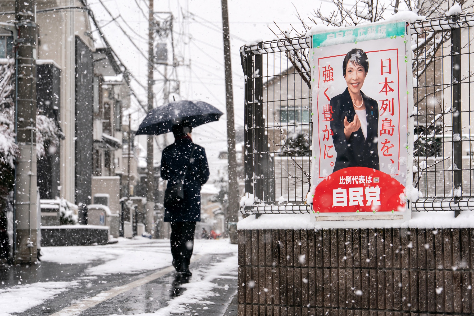 TOKYO, JAPAN - FEBRUARY 08: A pedestrian walks past an election poster bearing a photograph of Japanese Prime Minister and Liberal Democratic Party (LDP) President Sanae Takaichi displayed near a polling station on February 08, 2026 in Tokyo, Japan. Voters across the country headed to polls today as Japan's Lower House election was held. (Photo by Tomohiro Ohsumi/Getty Images) Photographer: Tomohiro Ohsumi/Getty Images AsiaPac