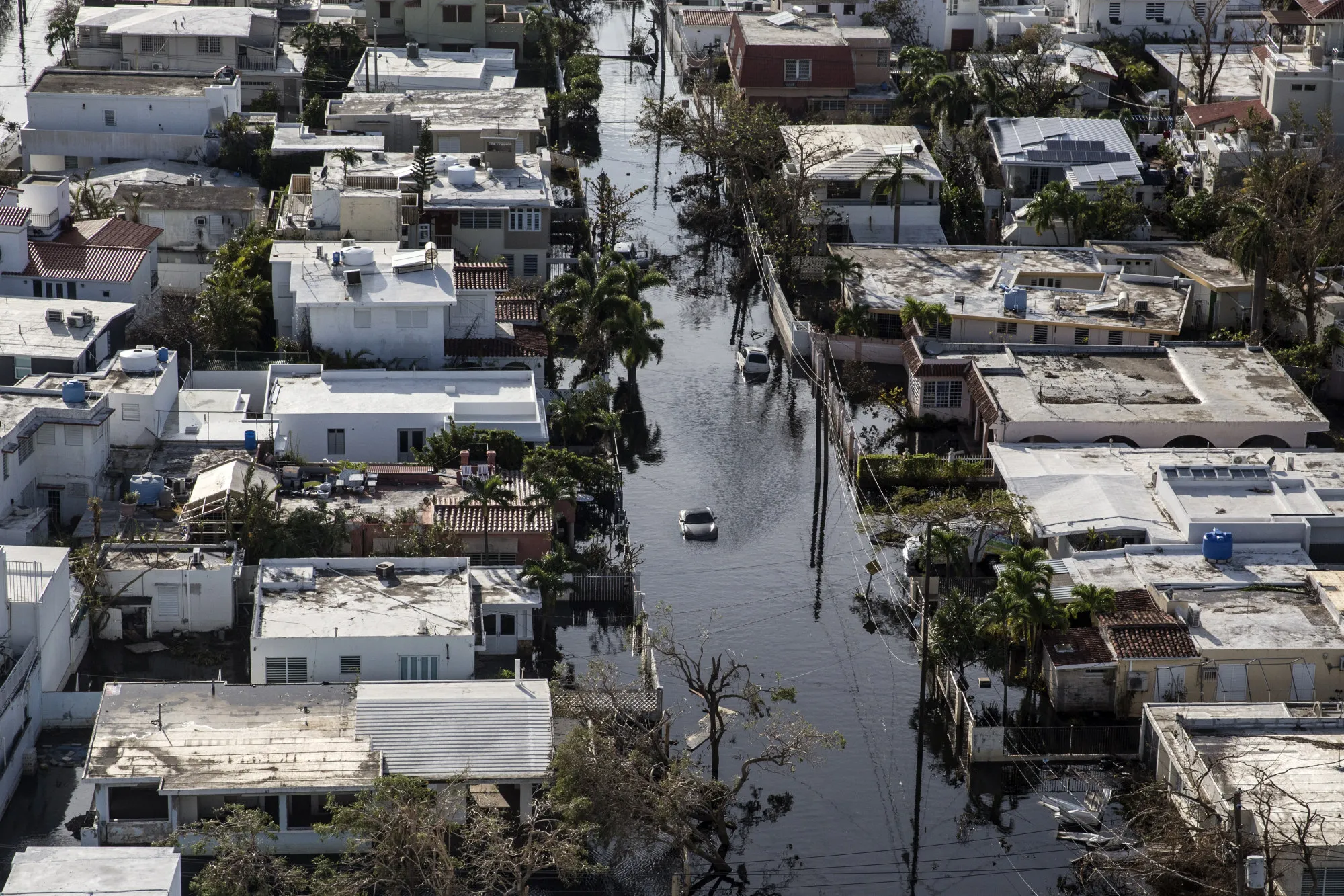 A vehicle drives through streets filled with floodwater near destroyed homes from Hurricane Maria&nbsp;in San Juan, Puerto Rico, on Sept. 25, 2017.