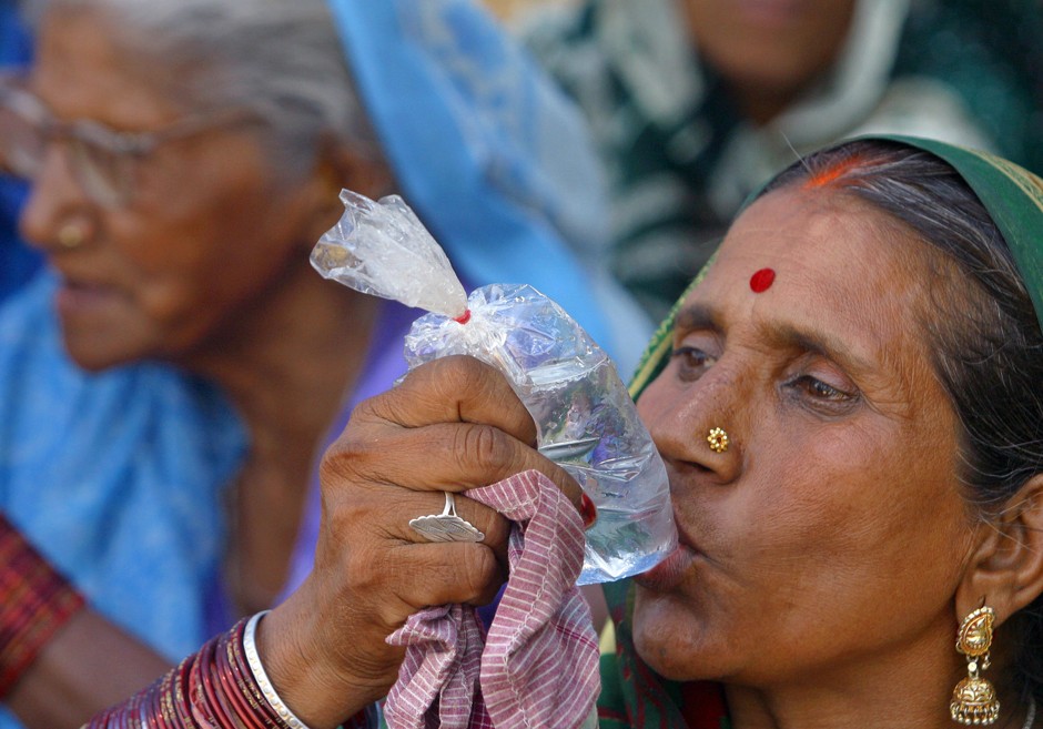 A woman drinks water from a plastic bag in Allahabad, India.