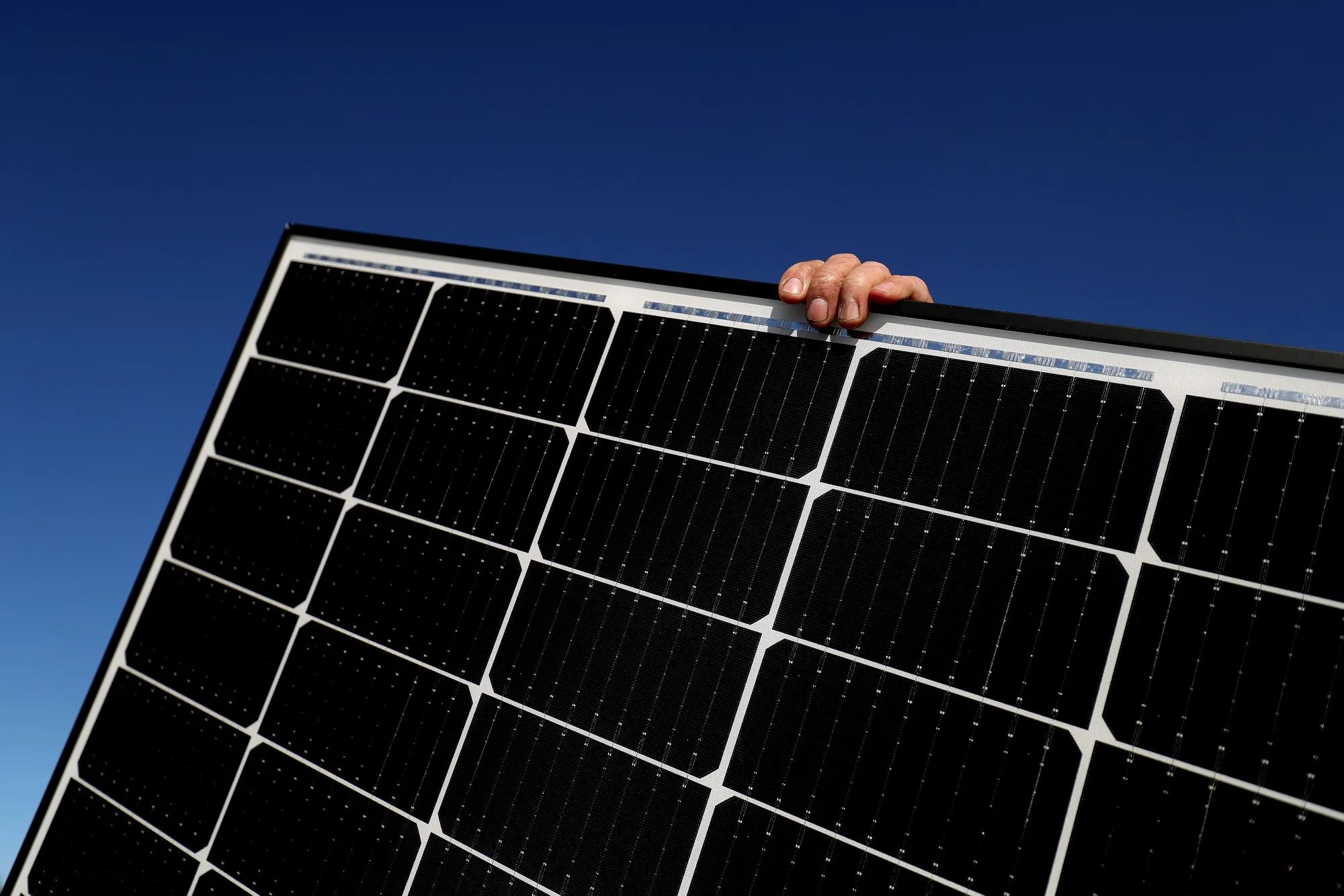 A person holds onto a solar panel&nbsp; before installing on a residential rooftop.