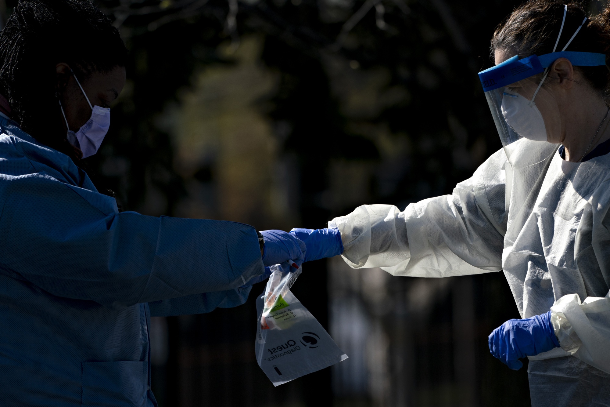 Healthcare workers places a vial into a Quest Diagnostics bag at a drive-thru testing site in Washington, D.C., on April 2.