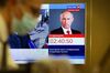 A television screen displays a countdown to the start of a live broadcast of Vladimir Putin at the Crowne Plaza World Trade Centre in Moscow.