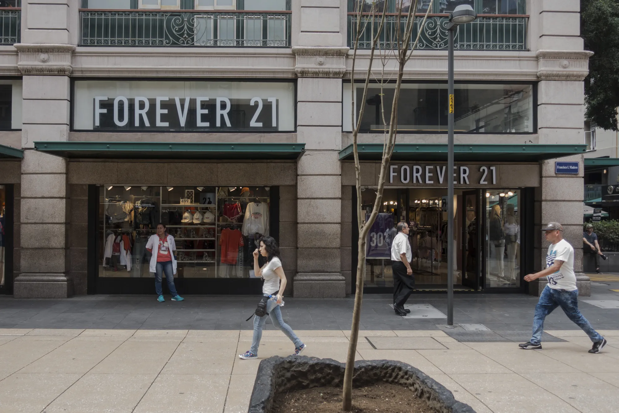 Pedestrians pass in front of a Forever 21 Inc. store.