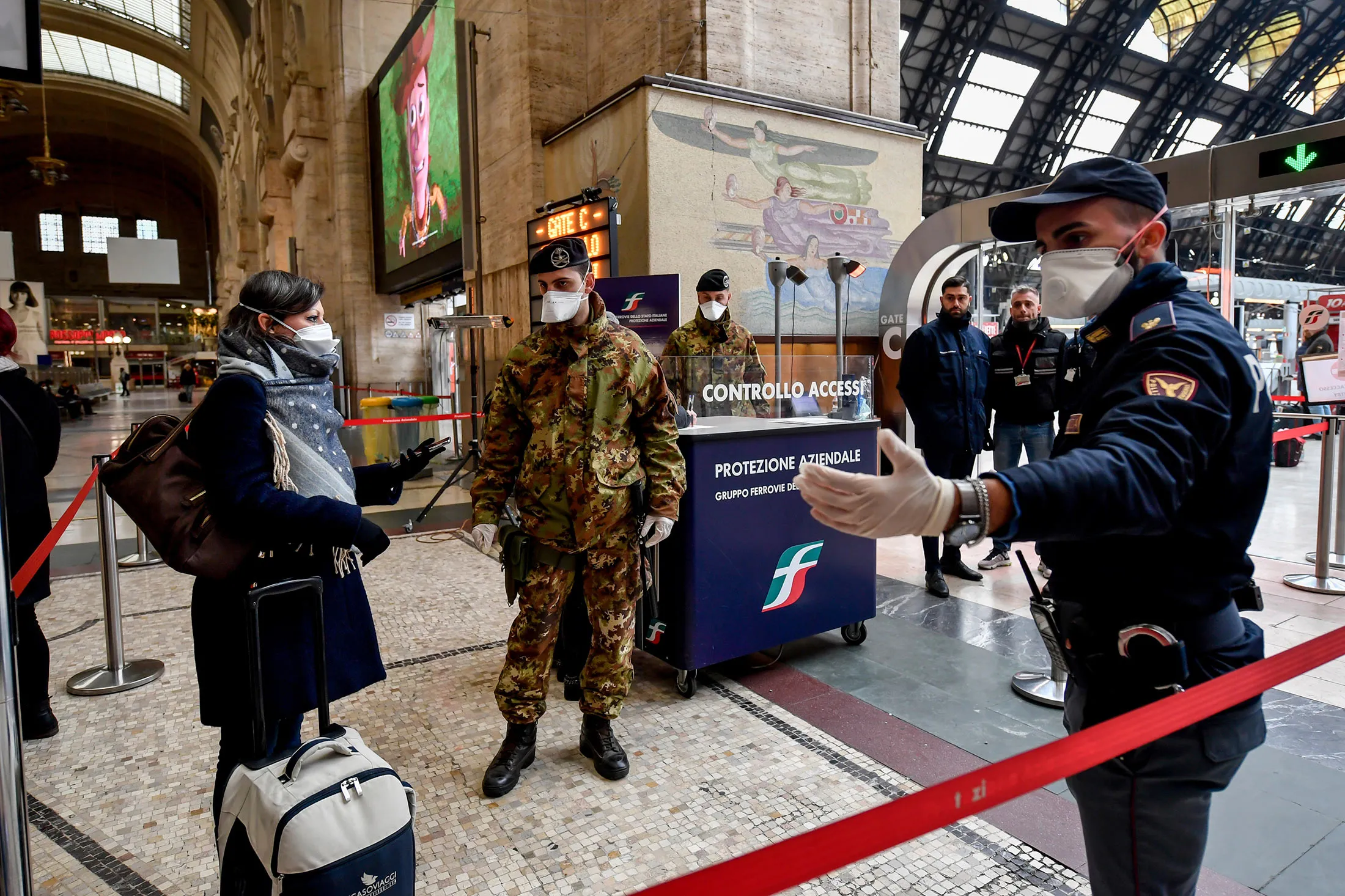 Police officers and soldiers check passengers leaving from Milan main train station in Italy on March 9.