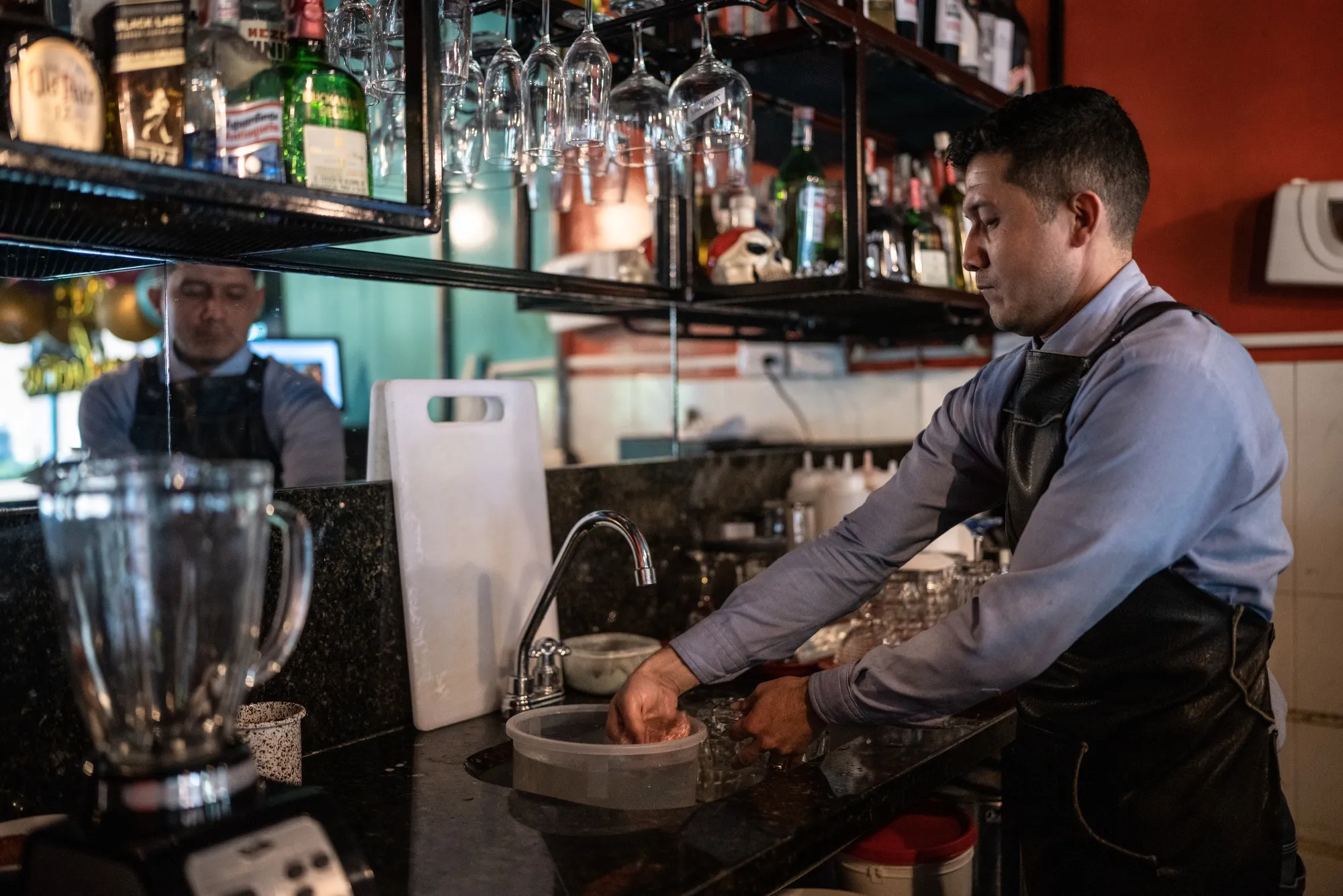 David Carima washes glasses with water collected in a bucket at Casa Frida, a restaurant in the Macarena district of Bogotá, Colombia on May 24.