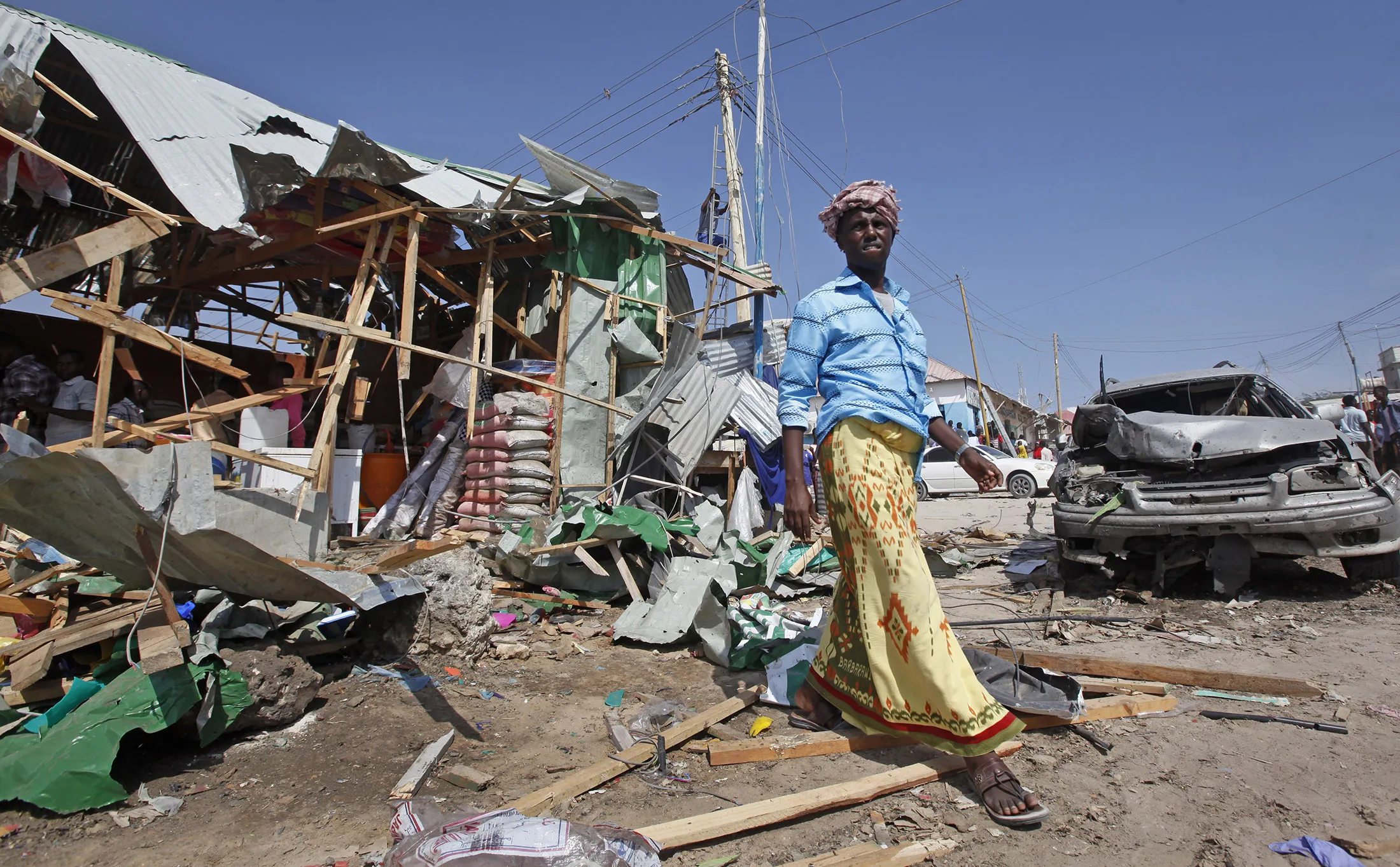 A man walks past the wreckage of shops destroyed by a blast in a market in the capital Mogadishu, Somalia, Sunday, Feb. 19, 2017. A Somali police officer says a blast at a busy market in the western part of Somalia's capital tore through shops and food stands and killed more than a dozen people and wounded many others.
