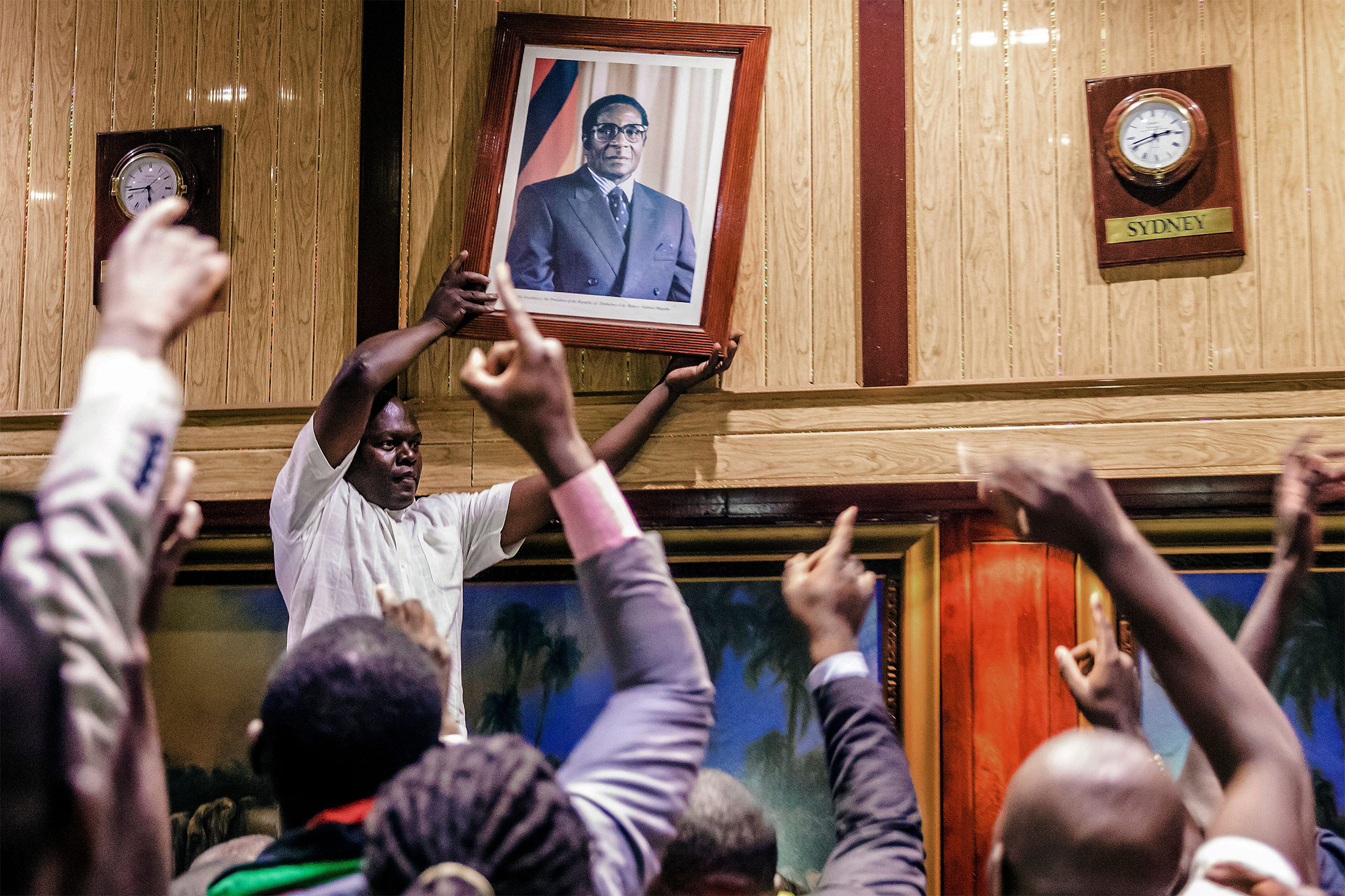 People remove the portrait of former Zimbabwean President Robert Mugabe, from the wall at the International Conference center, where parliament had their sitting, after his resignation on Nov. 21, 2017 in Harare.&nbsp;