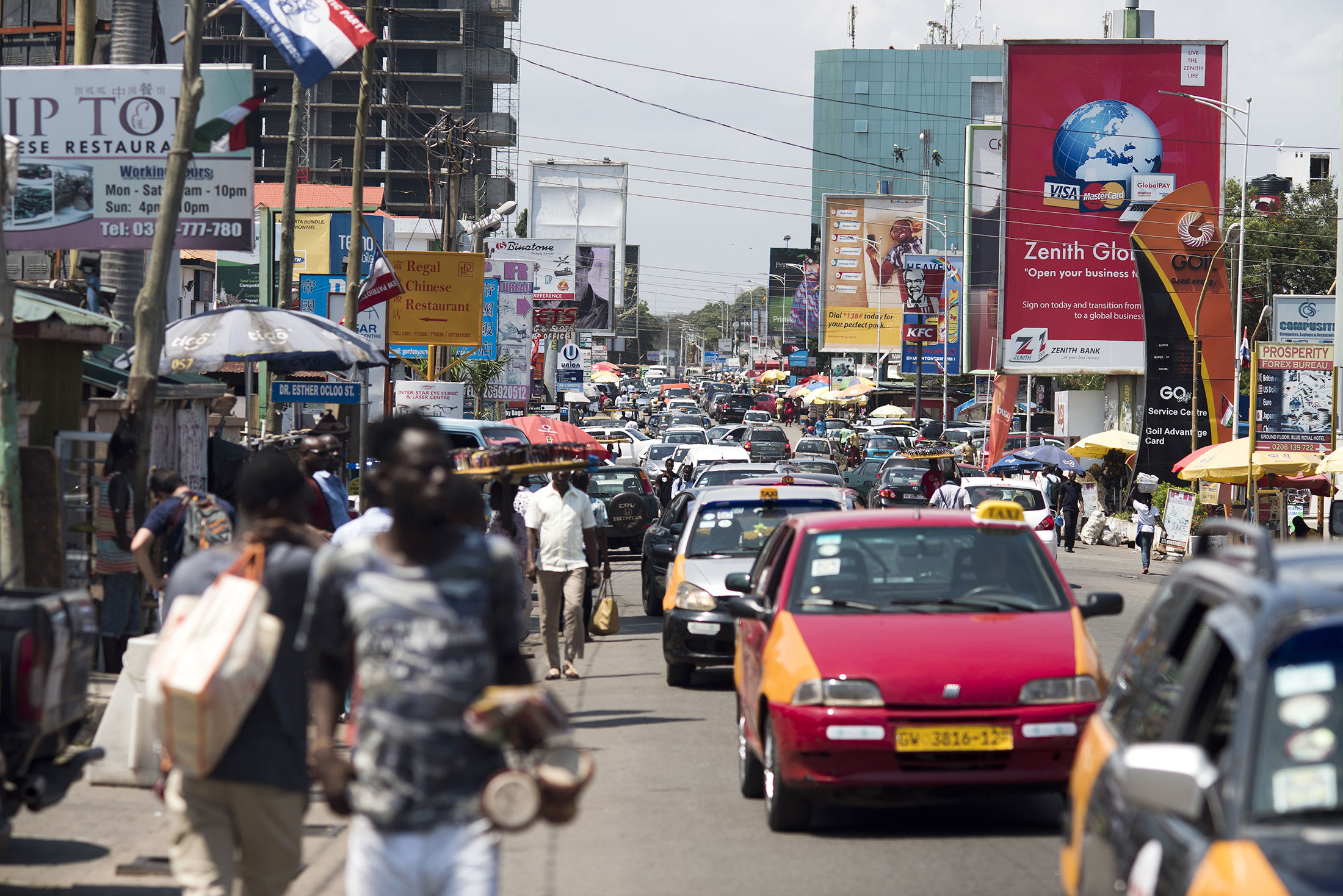 Road traffic passes business advertisements for Zenith Bank Plc and MTN Group Ltd. sit on a busy highway in Accra, Ghana.
