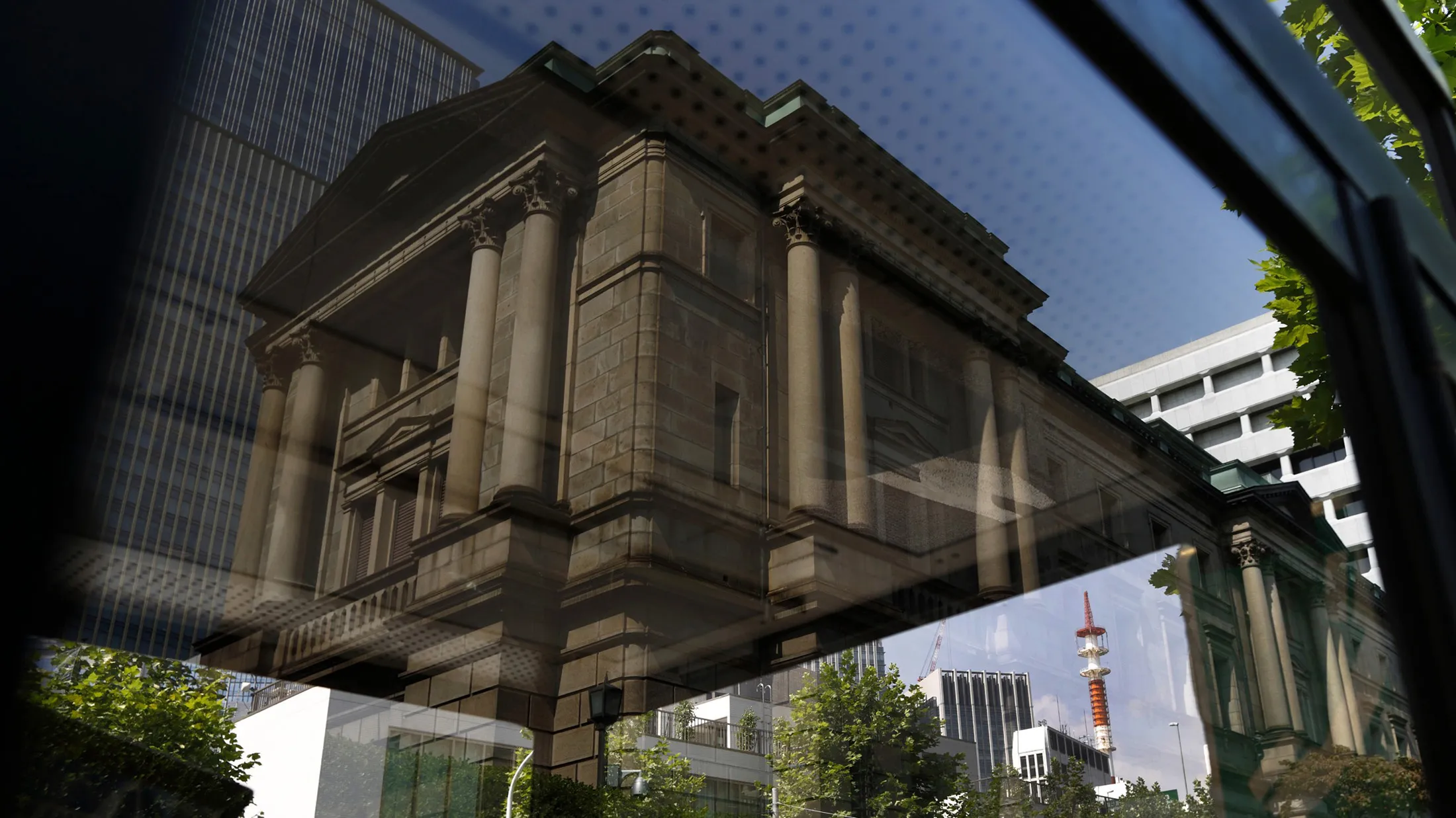 The Bank of Japan headquarters is reflected on a public phone booth in Tokyo.
