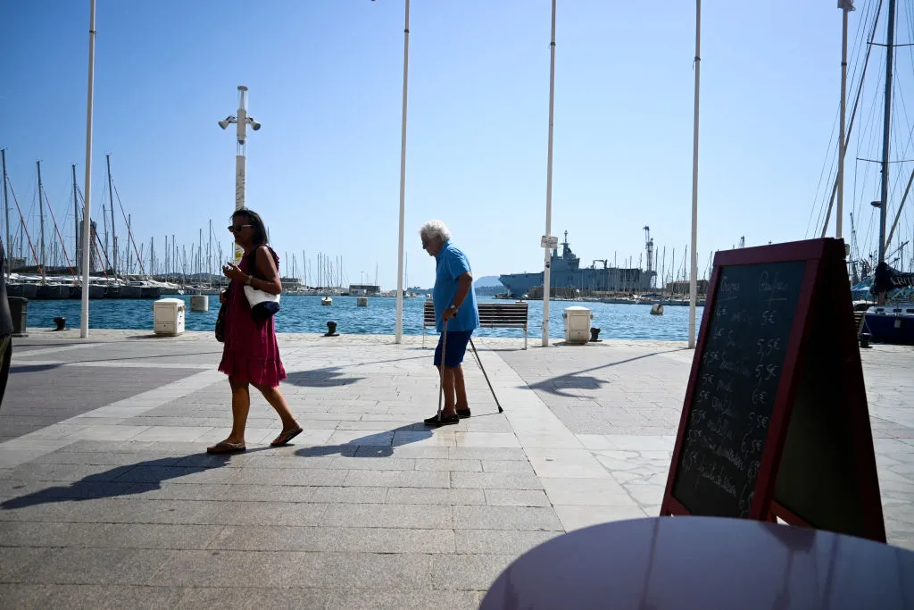 Elderly people walk by the harbour in Toulon, France.