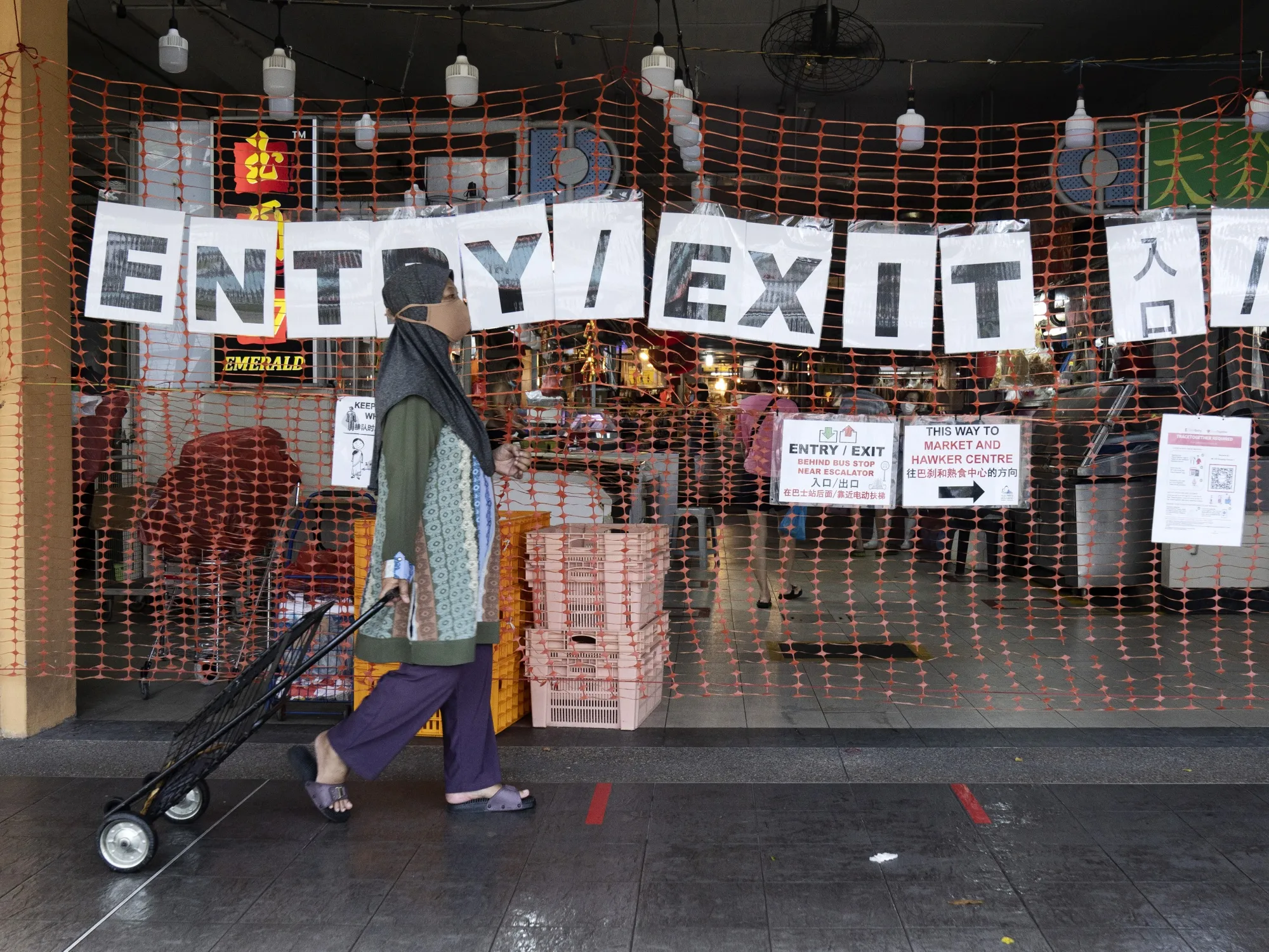 A sign directs customers to the entrance and exit points at a market in Singapore.