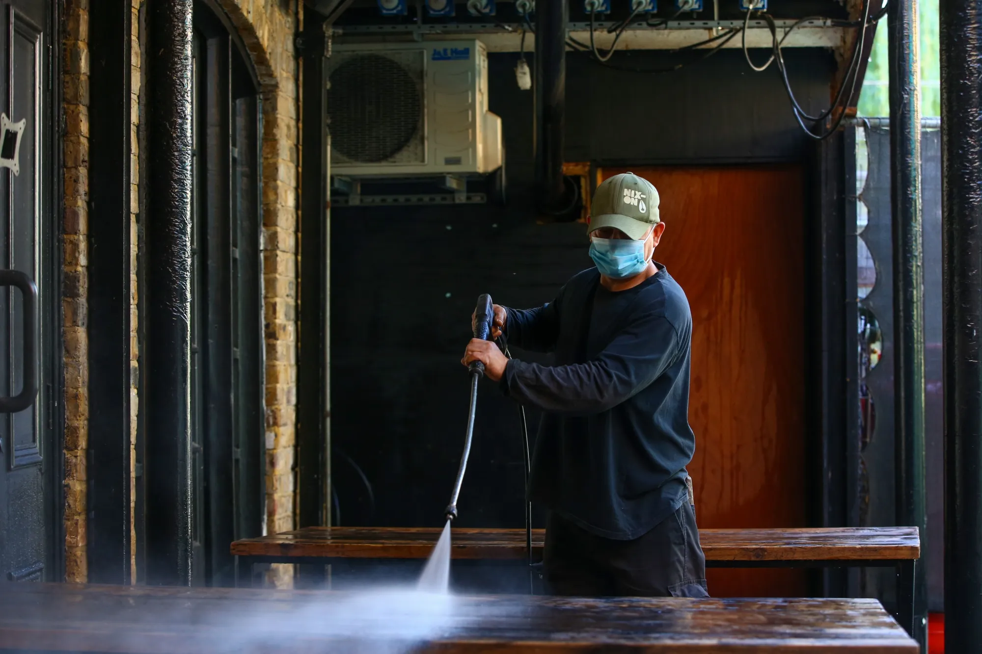 A worker pressure washes a table at Camden Market, as it re opens, in London on June 1, 2020.&nbsp;