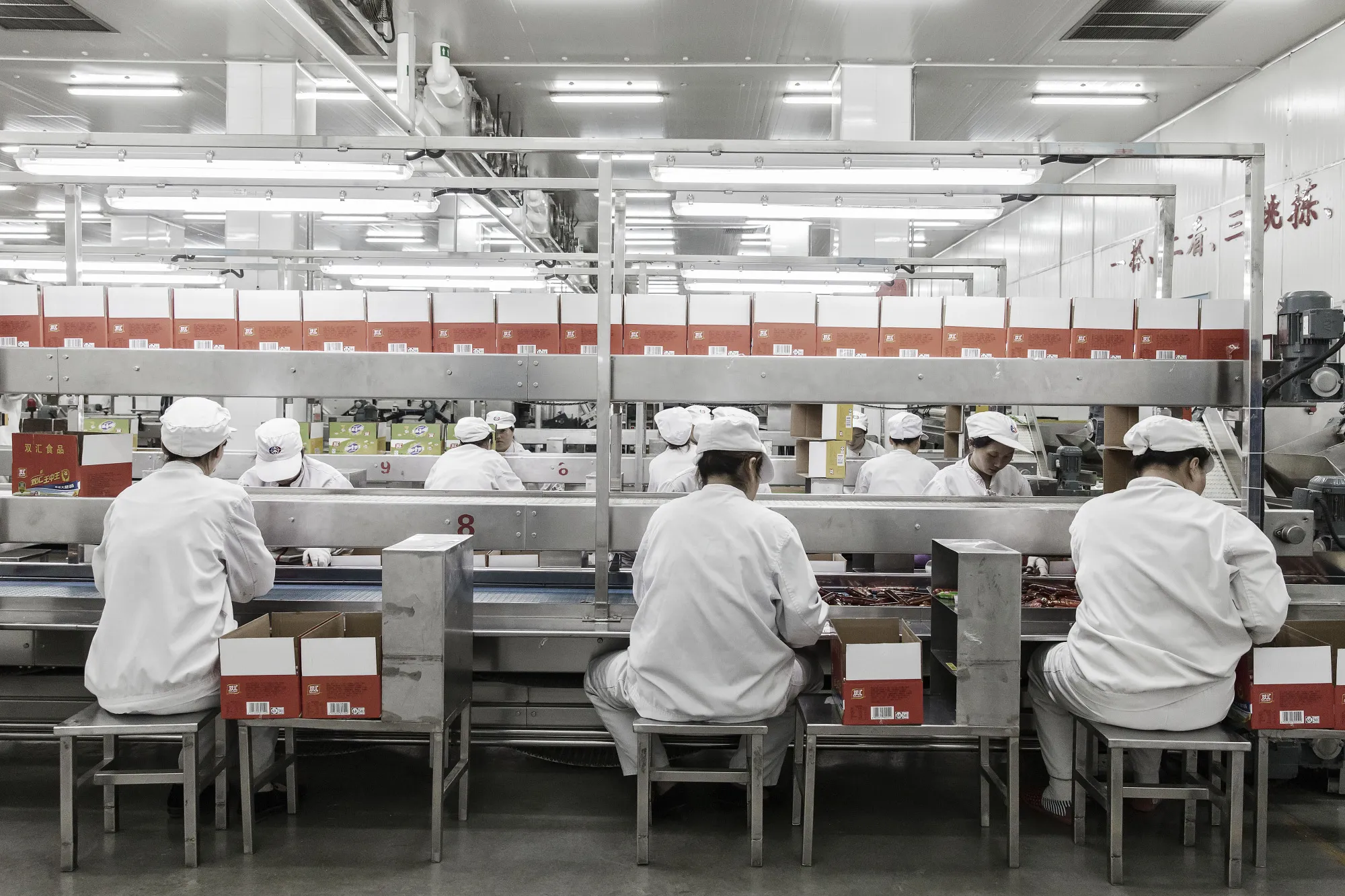 Workers sort packaged sausages on a production line that manufactures Shuanghui branded sausages at a WH Group Ltd. facility in Zhengzhou, China, on Thursday, April 13, 2017.&nbsp;