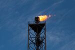 A flame blazes on top of a gas burn off venting pipe. Photographer: Simon Dawson
