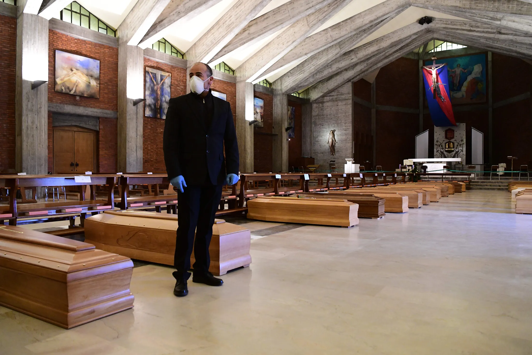 A pallbearer stands next to coffins of the deceased in the church of San Giuseppe in Seriate, Lombardy, on March 26.