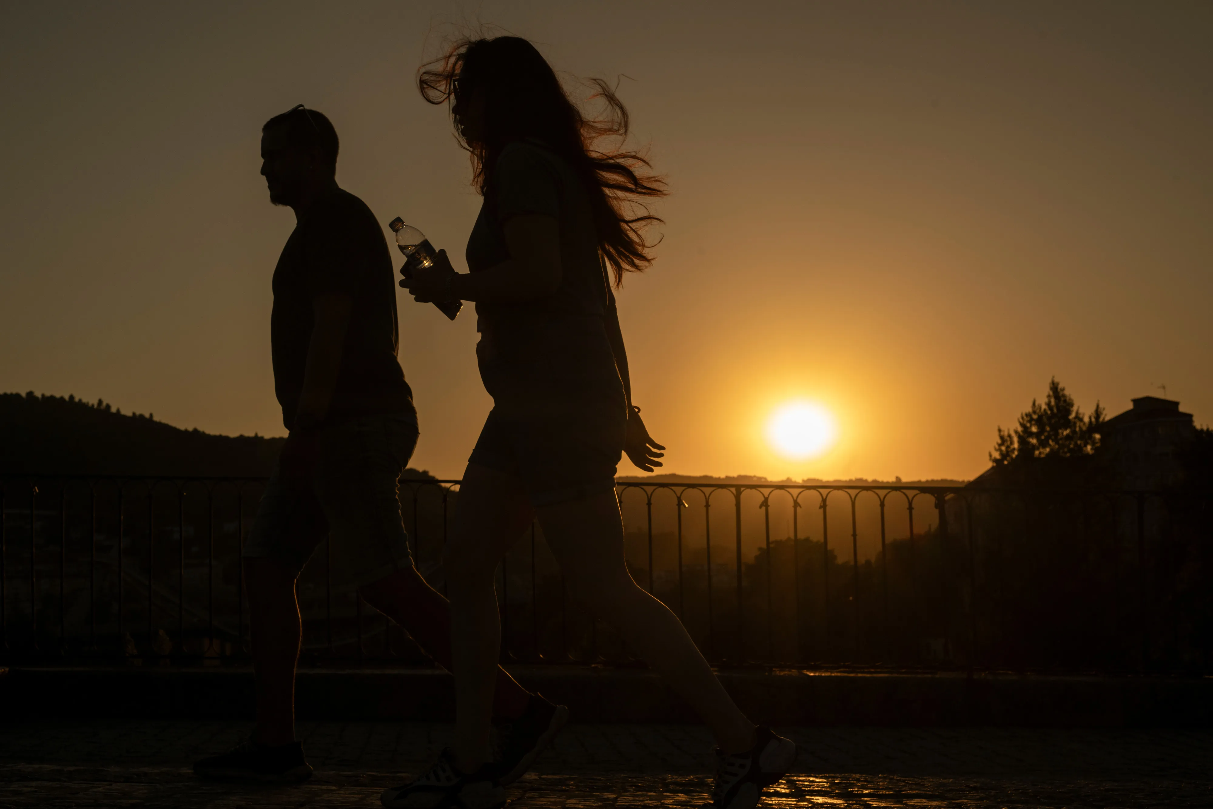 Residents walk along a footbridge as the sun sets during a heatwave in Ourense, Spain, on Aug. 8.