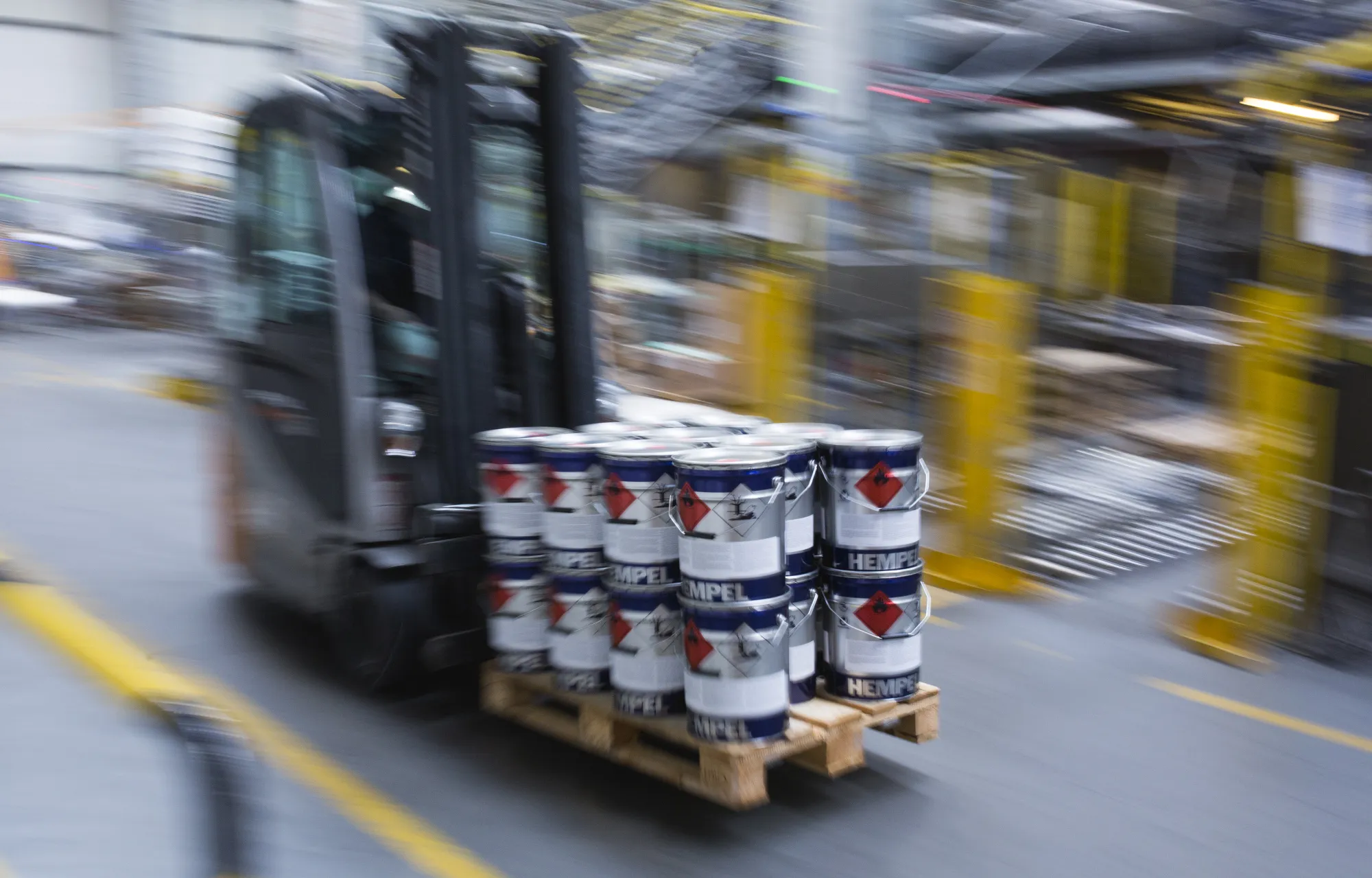 Employees use forklifts to move finished pallets of coatings from the production line inside the Hempel A/S coatings manufacturing facility in Buk, Poland, on Tuesday, July 5, 2016.&nbsp;