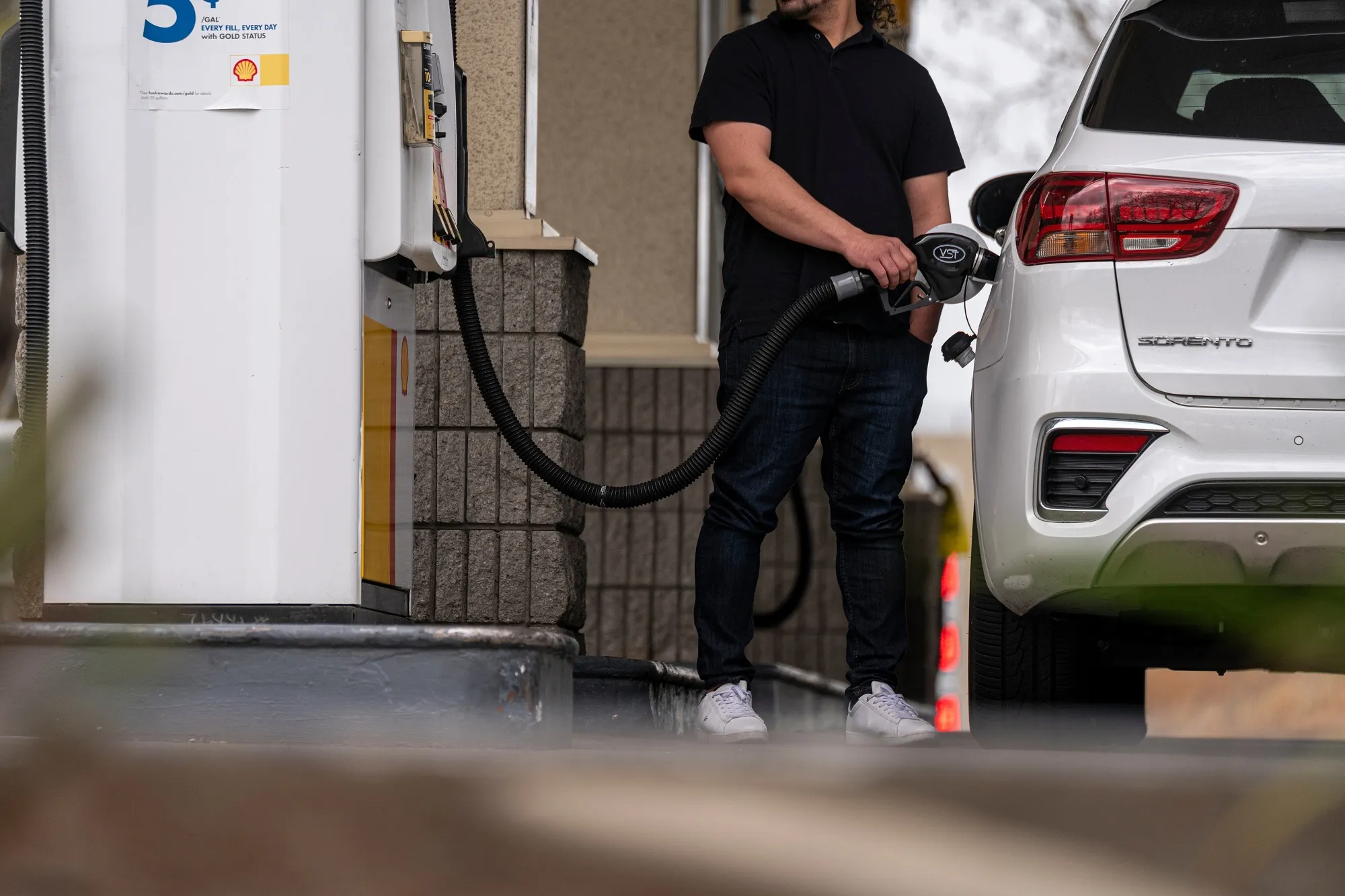 A driver holds a fuel nozzle at a gas station. (Photographer: David Paul Morris/Bloomberg)
