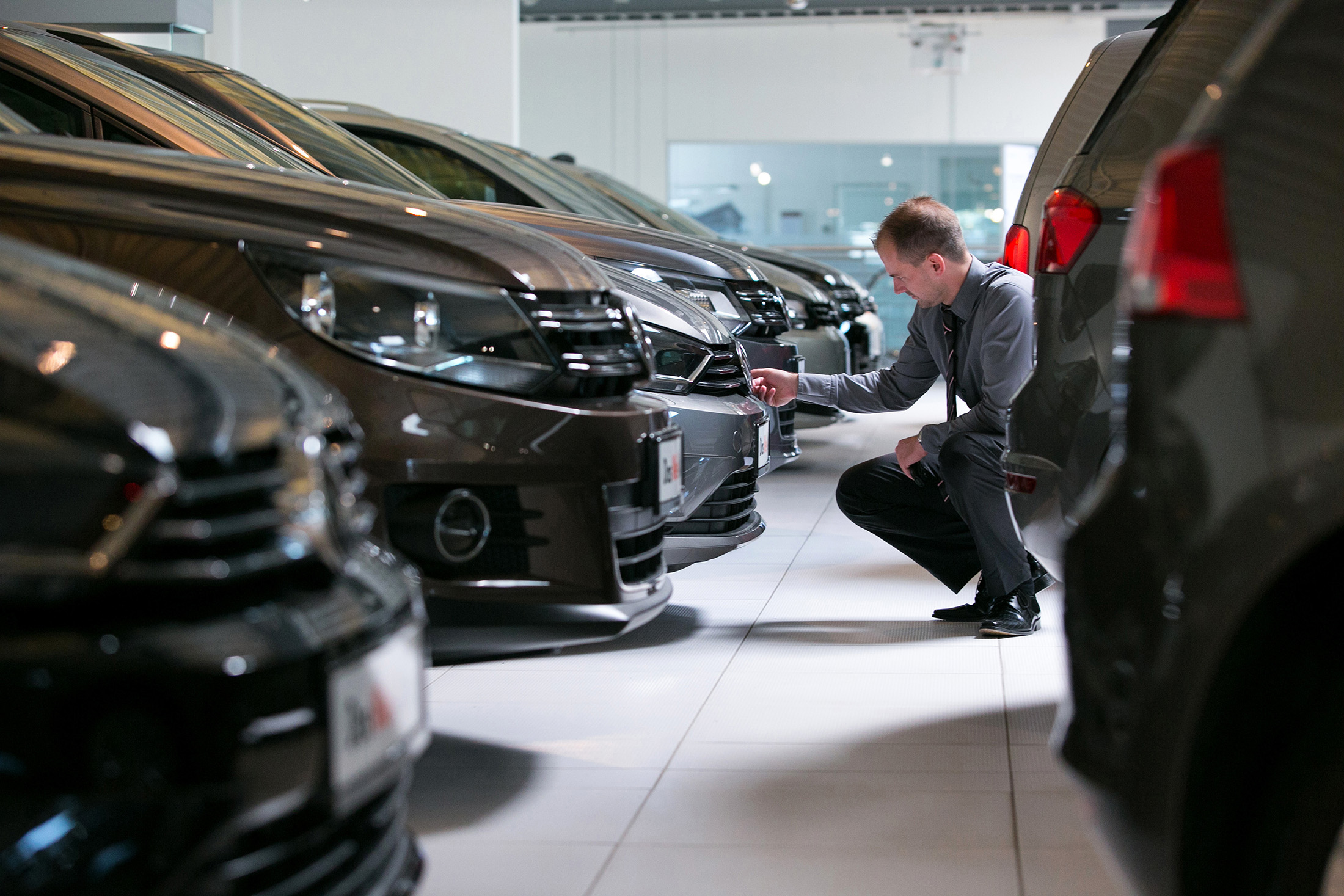 An employee inspects a Volkswagen automobile at a Volkswagen AG showroom in Berlin, Germany.
