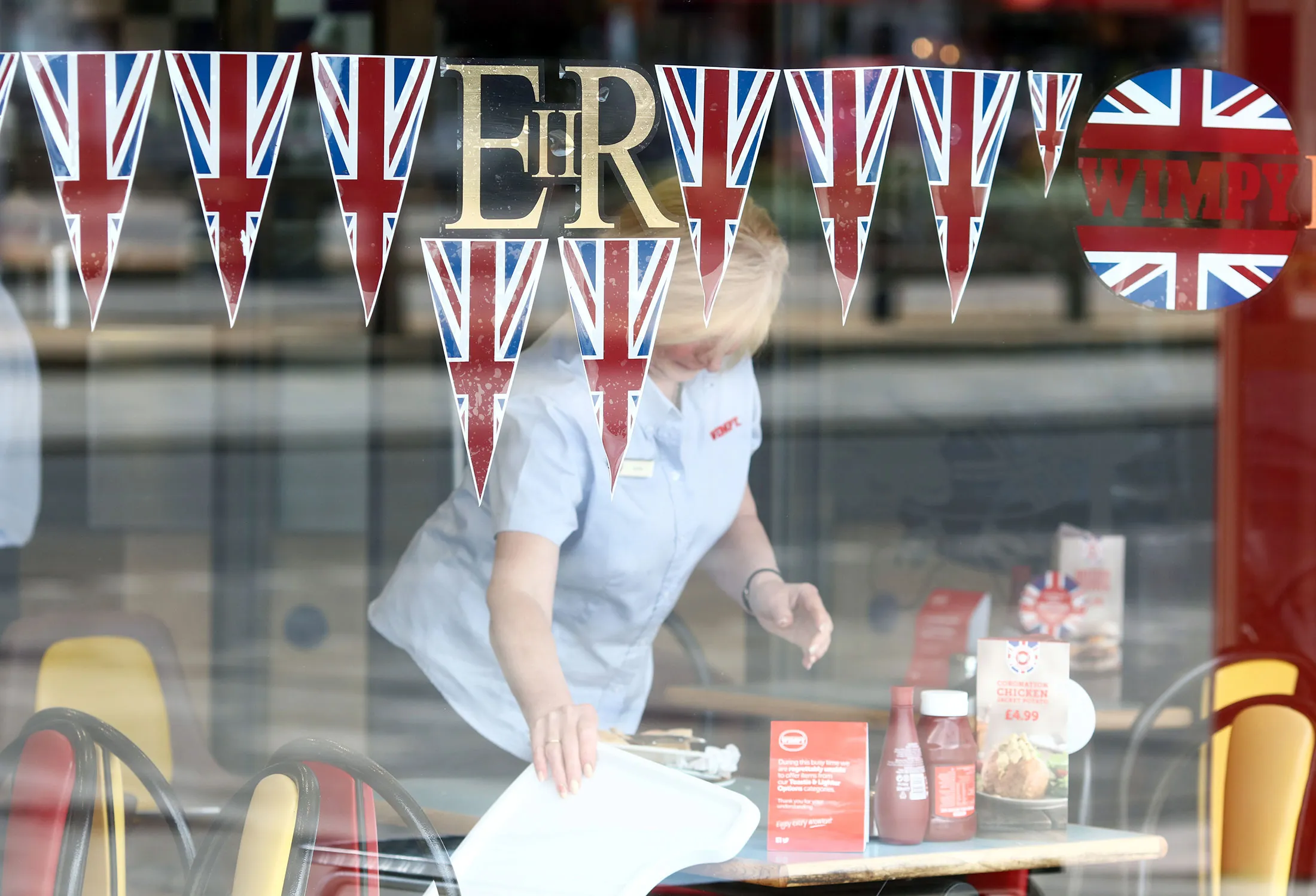 A waitress clears a table inside a restaurant in Southend, U.K.
