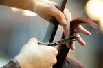 Hairdresser trimming blond hair with scissors
