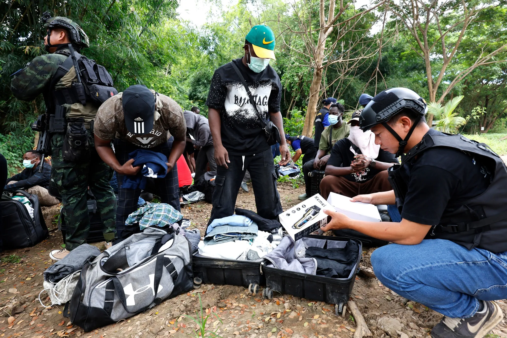 Thai officials inspecting the belongings of a worker in a suspected cyber scam center in Myanmar.