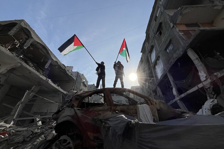 Children wave Palestinian flags on a wrecked car in Jabalia, Gaza.
