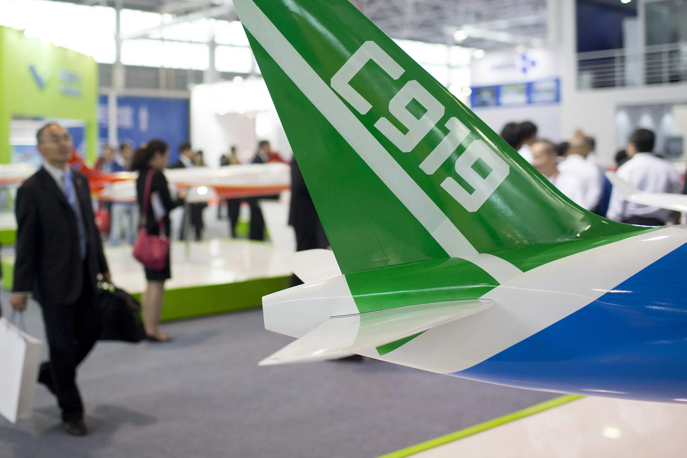 Attendees walk pass a COMAC C919 aircraft during the China International Aviation &amp; Aerospace Exhibition in Zhuhai, Guangdong province, China, on Tuesday, Nov. 11, 2014. The air show takes place from Nov. 11-16.

