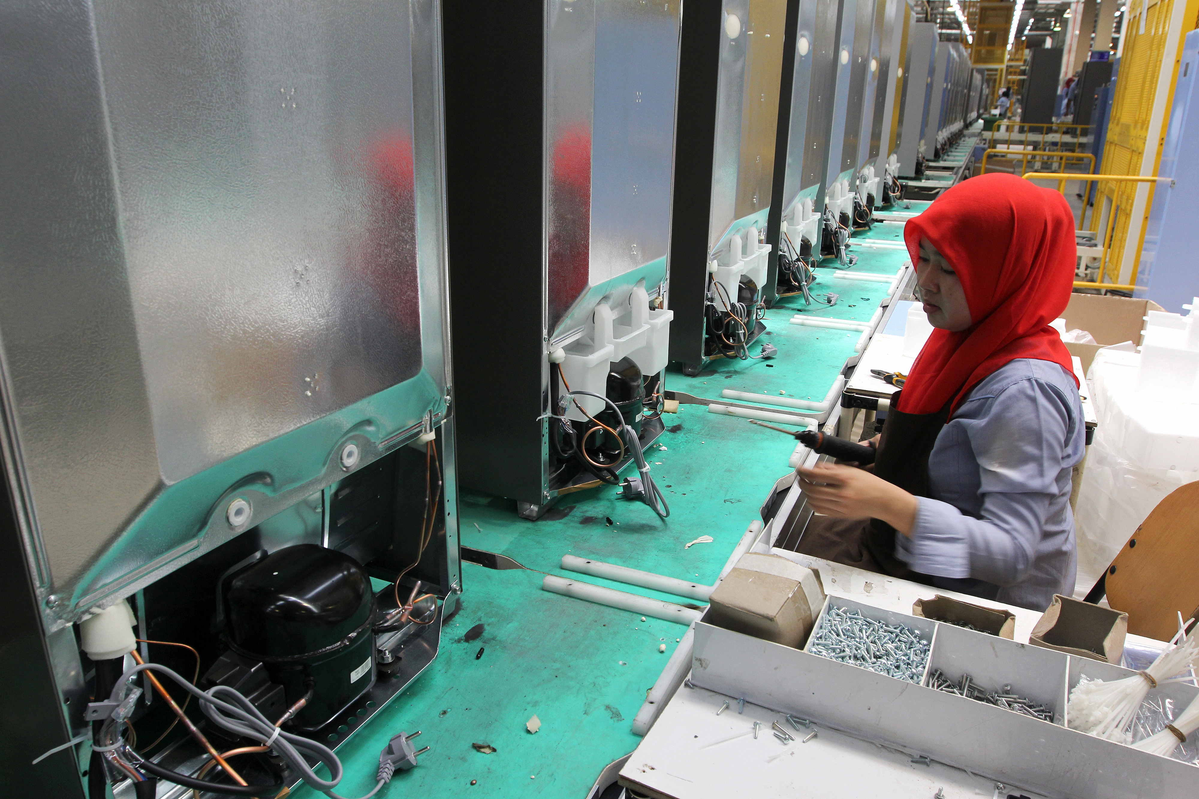 An employee installs components onto refrigerators on the production line at the Sharp Corp. factory in Karawang, Indonesia.

