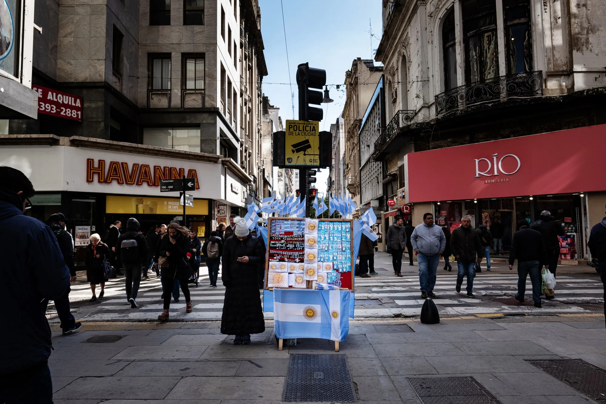 Pedestrians walk past a vendor selling souvenirs on the street in Buenos Aires, Argentina.