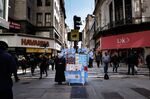 Pedestrians walk past a vendor selling souvenirs on the street in Buenos Aires, Argentina.
