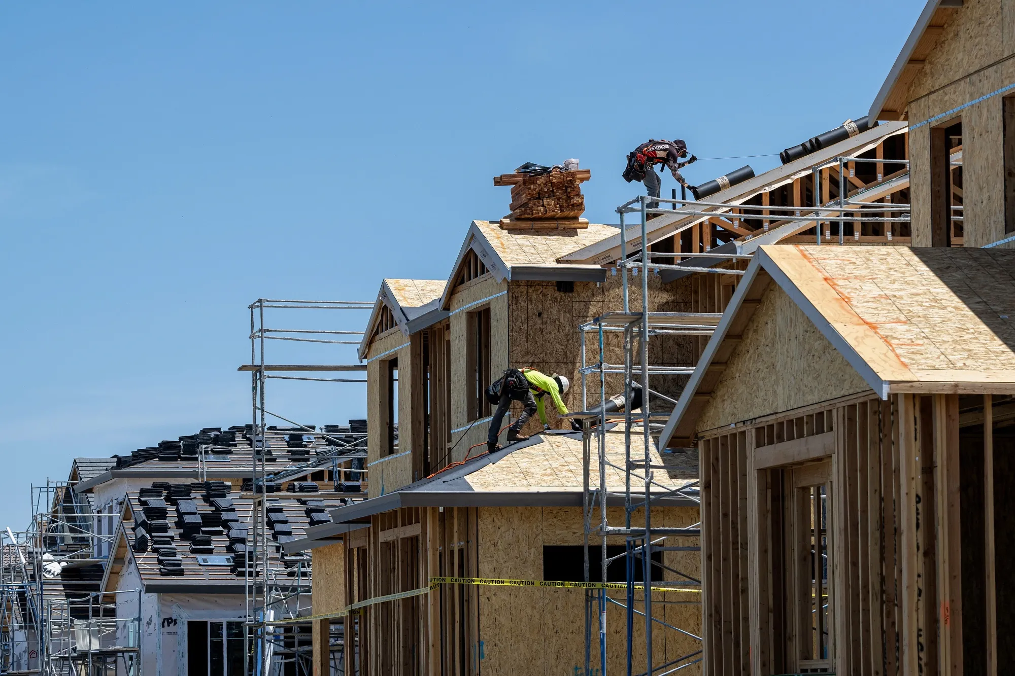 Workers install roofing on a home under construction in Vacaville, California.