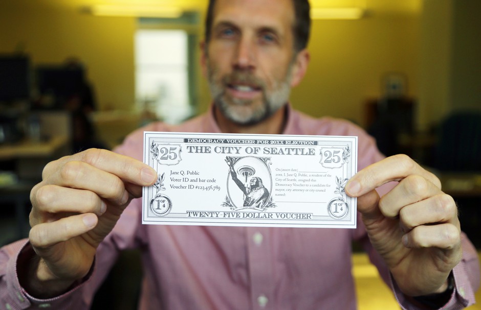 The author of Seattle's &quot;democracy voucher&quot; initiative holding up a $25 voucher.