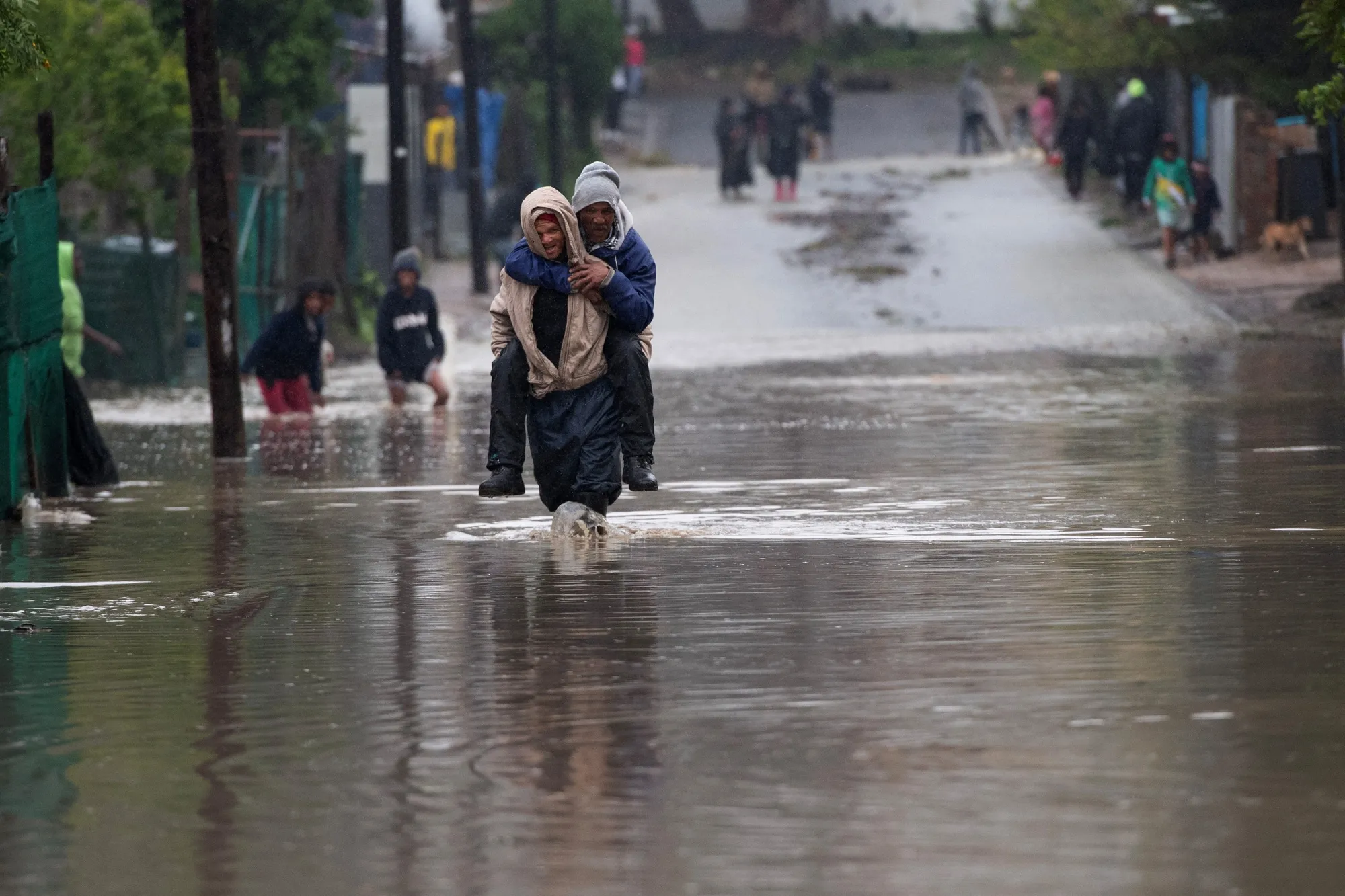 A man carries an elderly man across a flooded road during heavy flooding following a storm in Sir Lowry's Village, South Africa, on Sept. 25.
