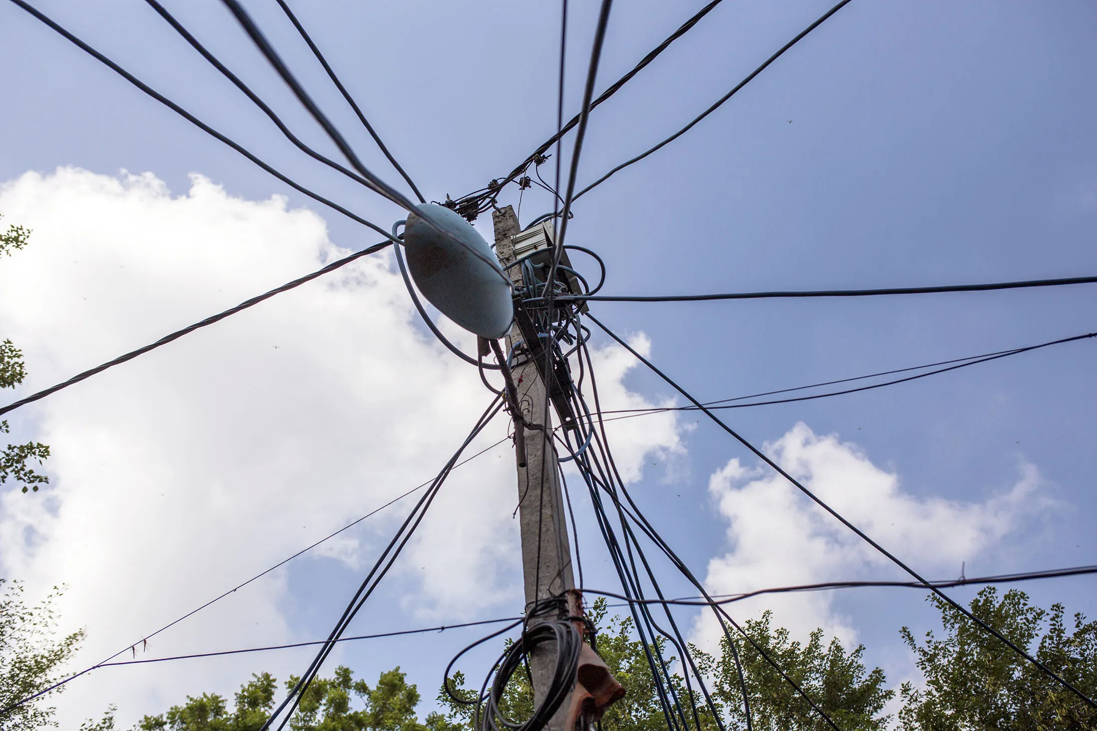 Power and utility cables hang from a pole in Khilona Wala Bagh slum cluster in New Delhi on Tuesday, Sept. 6, 2017. Slum dwellers steal electricity and refuse to pay their bills, so the Tata Power Co.’s joint venture with the Delhi state government hired women living in the slums to go around the slums, knocking on neighbors’ doors and persuading, coaxing, cajoling and nagging them to pay their power bills.
