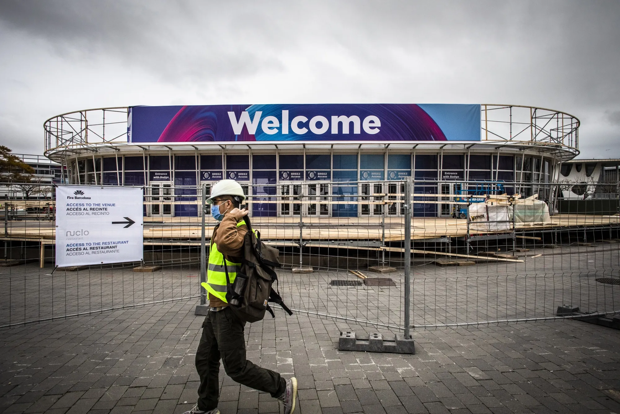 A worker wearing a protective face mask walks past the entrance to the venue for the Mobile World Congress in Barcelona, on Feb. 12.