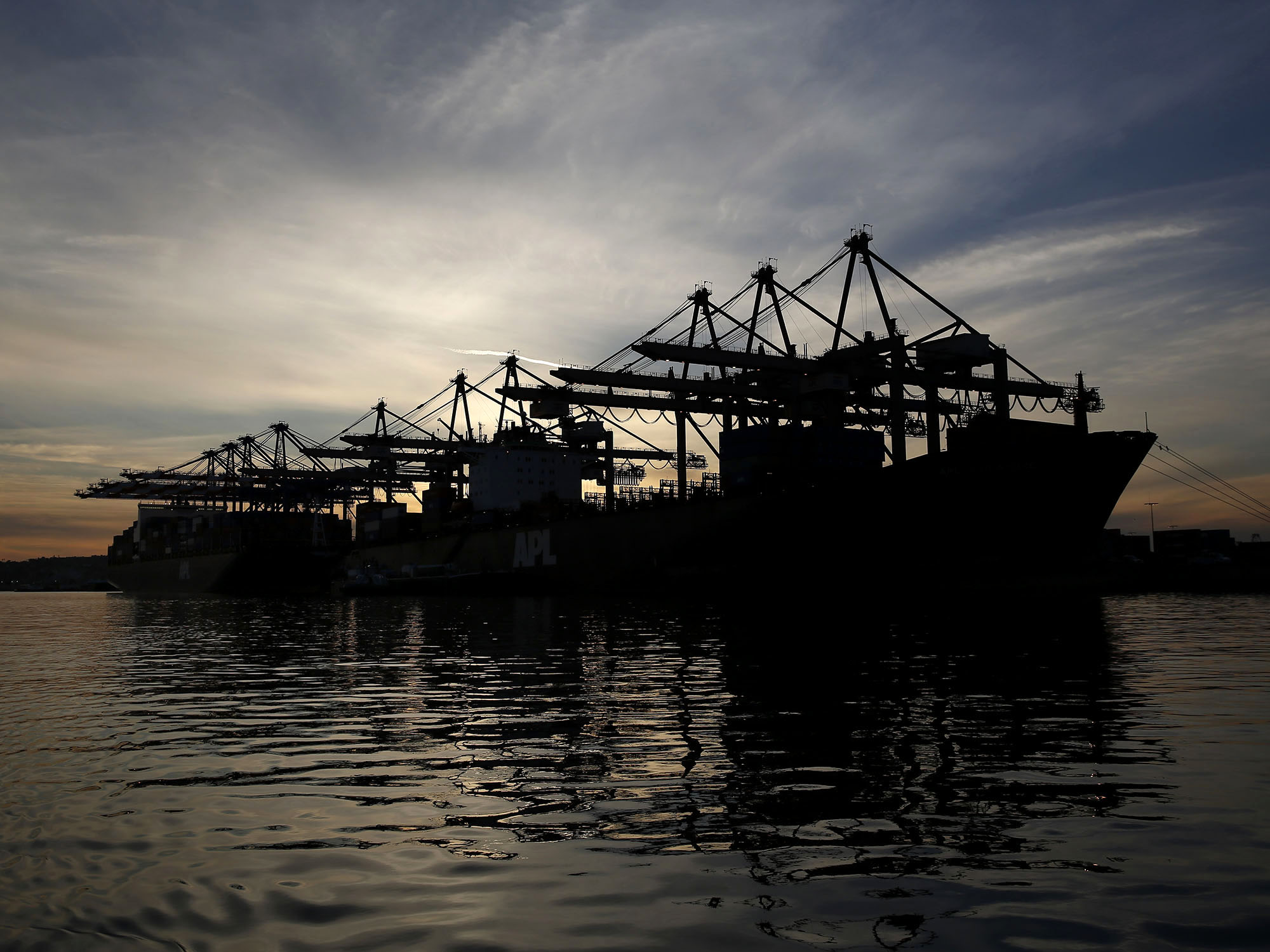 The silhouette of cranes are seen unloading container ships at the Port of Los Angeles in San Pedro, California.