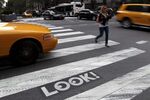 Pedestrians and traffic move past a &quot;Look!&quot; sign on the crosswalk at the intersection of 42nd St. and 2nd Avenue in New York.