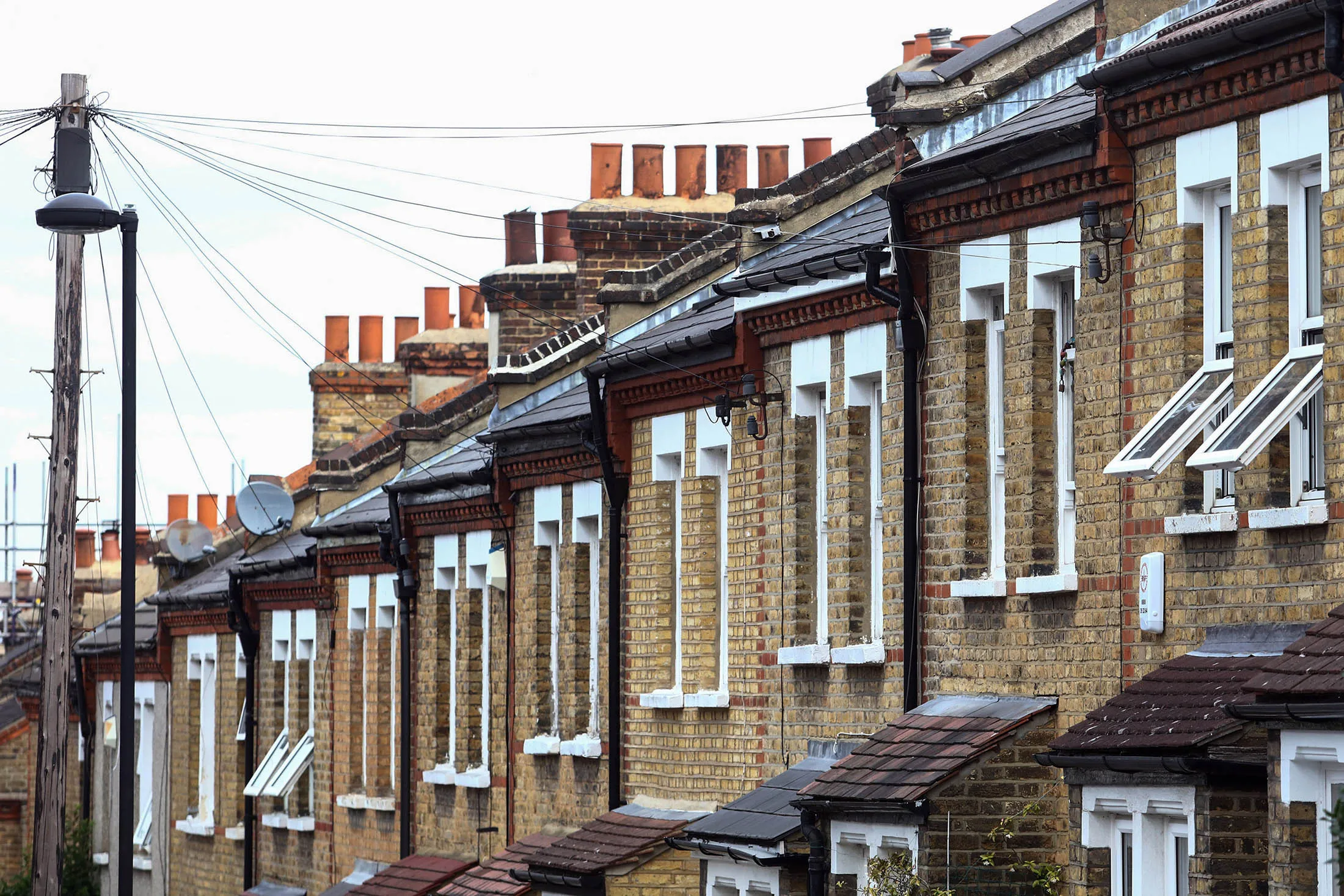 Telephone lines lead to a row of terraced houses standing on a hilltop street in southeast London, U.K., on Thursday, July 21, 2016. London's seven-year housing boom may be about to end after the U.K. voted to leave the European Union.

