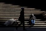 A homeless person sleeps on the steps of Federal Hall on Wall St. in New York City