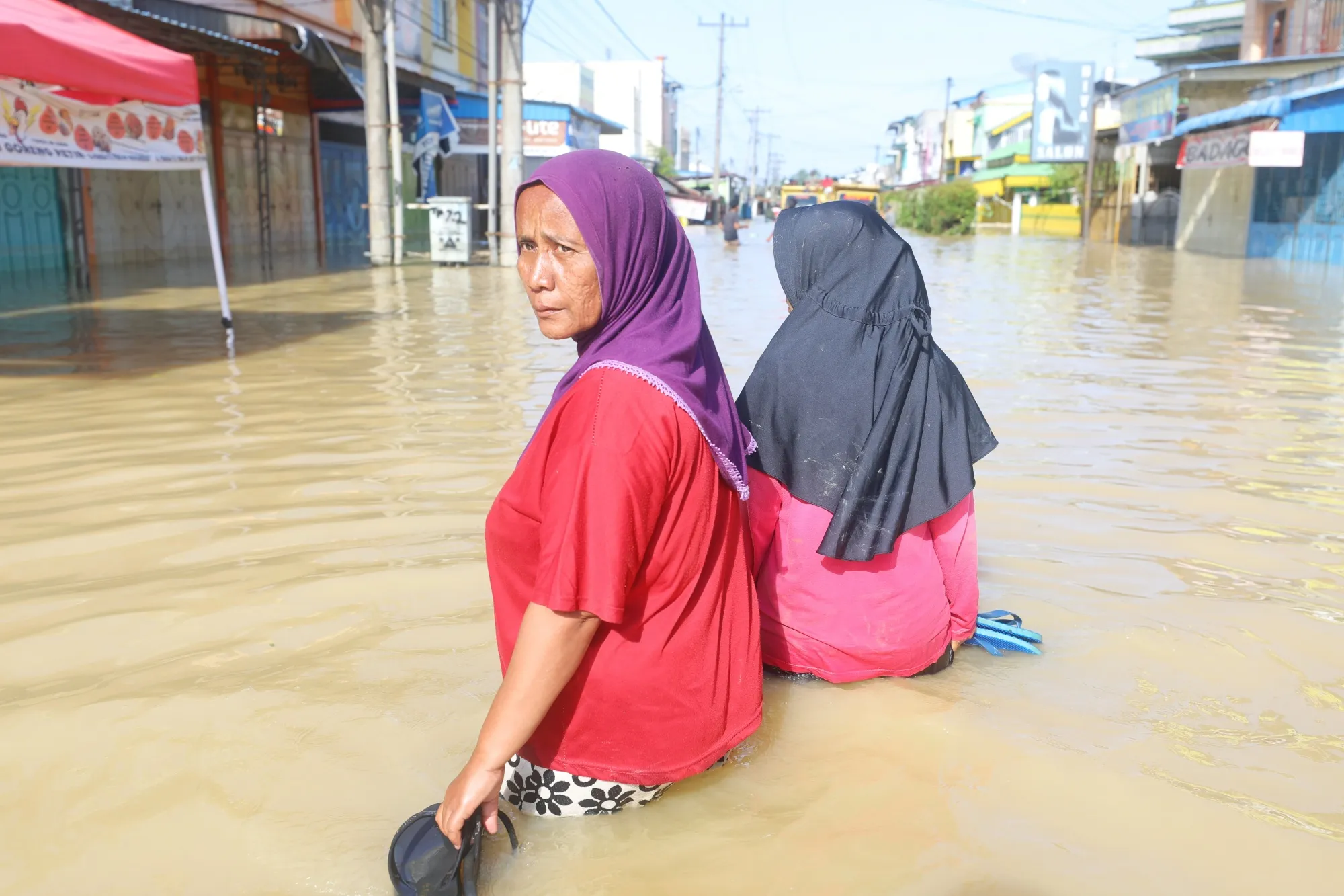 People wade through a flooded road in Sumatra, Indonesia on Nov. 30.
