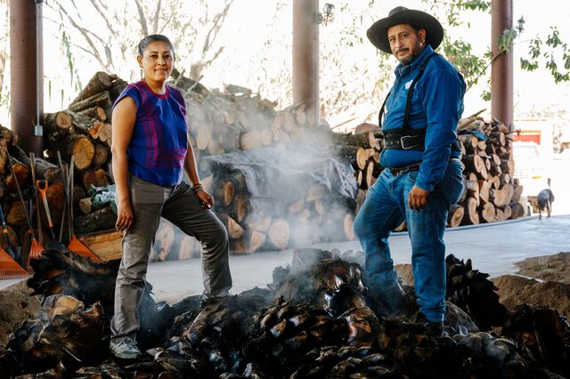 Family members behind Real Minero mezcal standing on top of some freshly roasted piñas.
