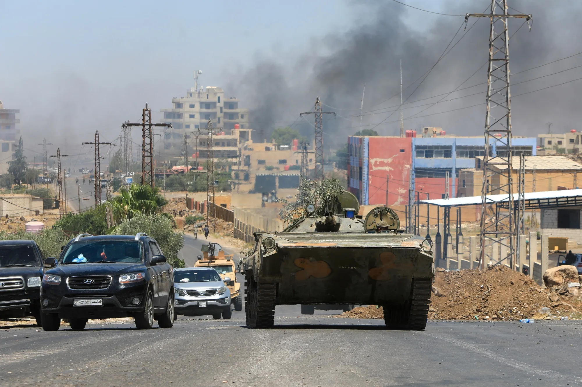 Syria's security forces drive through the predominantly Druze city of Suwayda as smoke rises following Israeli bombardment on July 15.