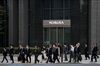 Pedestrians walk past a branch of Nomura Securities Co., a unit of Nomura Holdings Inc., in Tokyo.