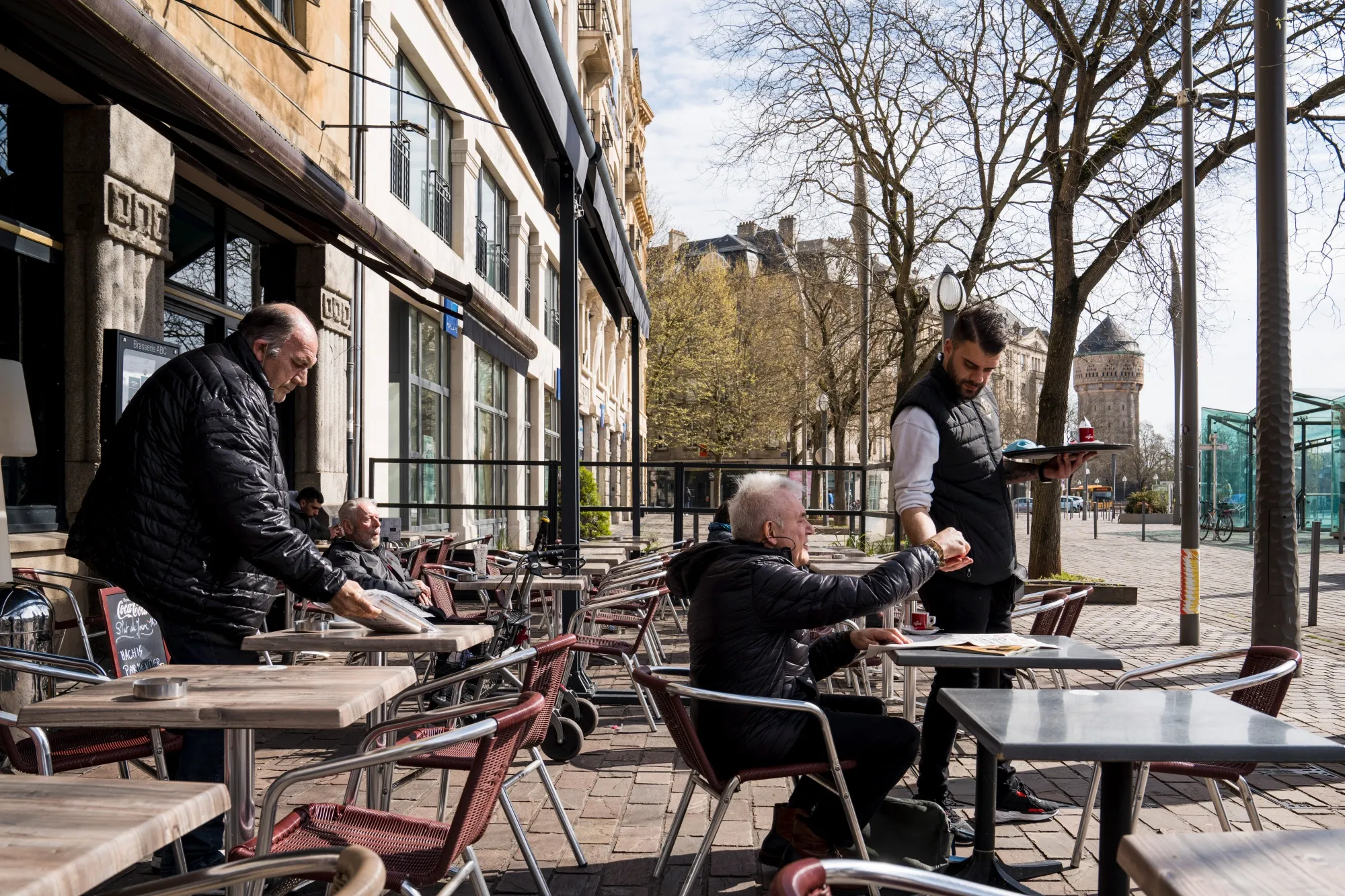 A waiter serves a customer on the terrace area of a cafe in Metz.
