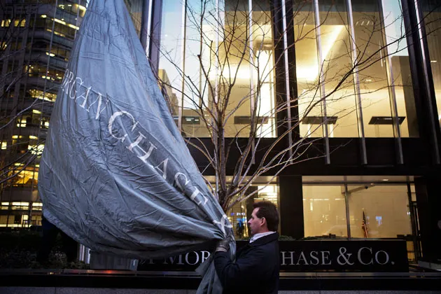 Workers raise a flag at JPMorgan Chase’s headquarters in New York before an annual Investor Day conference on Feb. 26