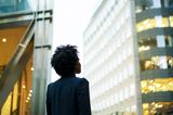 Woman looking up at office buildings RF